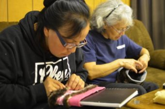 Stacey Skan and Anna Frisby sew sea otter fur onto knit headbands as a donation to Hydaburg’s Artist Cooperative. (Photo by Ruth Eddy/KRBD)