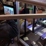 Sam Bornstein makes adjustments on the touchscreen of Juneau Makerspace's 3D printer.