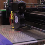 A closeup of the print head of the 3D printer at Juneau Makerspace as it lays down the outline of a plastic object it is printing.