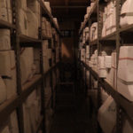 An aisle between two rows of shelves full of the ceramic molds in Juneau Makerspace when they moved in