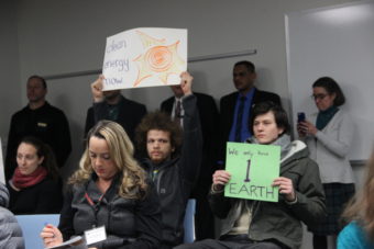 Activists with Alaksa Rising Tide held up signs during the Nov. 18, 2015 BLM lease sale. (Photo by Rachel Waldholz/APRN)