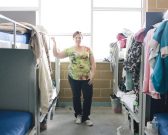 Jennifer Carter, 30, stands in a dormitory area that she shares with her two young children at The Road Home Community Winter Shelter facility in Midvale, Utah. Cayce Clifford for NPR