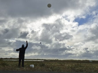 William Wells releases a weather balloon on Alaska's St. Paul Island. (Photo by John Ryan/KUCB)