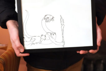 Ambrose Bucy holds one of his drawings from a past exhibition at the Alaska Robotics Student Show of the Comic Arts. (Photo by Annie Bartholomew/KTOO)