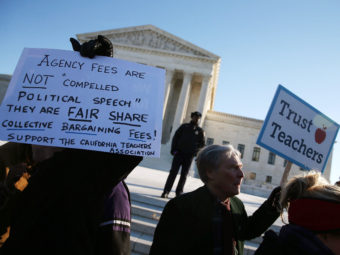 People for and against unions hold up signs Monday in front of the U.S. Supreme Court building in Washington. The court was hearing arguments in Friedrichs v. California Teachers Association. Justices will decide whether California and other states can make nonunion public employees covered by union contracts pay partial dues. Mark Wilson/Getty Images