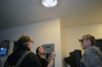 Resident Dennis Wharton, (left), and contractor David Phillips, (right), look on as Will Noel tests the electricity at the Channel View Apartments after one of the building's units caught fire Sunday afternoon. (Photo by Jennifer Canfield/KTOO)