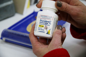 Michelle Pattengill, a technician at L&S Pharmacy in Charleston, Missouri, holds a bottle of oxycodone. (Bram Sable-Smith/Side Effects Public Media/KBIA)