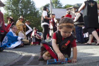 Jeffrey Mark, Tsimshian from Anchorage, plays with train while waiting for his group's turn to march during a processional and grand entrance on Wednesday, June 8, 2016, near Juneau, Alaska. Celebration is a biennial festival of Tlingit, Haida and Tsimshian tribal members put on by the Sealaska Heritage Institute. (Photo by Rashah McChesney/KTOO)