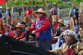 John Martin asks for permission come ashore. He told the crowd, "Today, we are practicing that our Tlingit, Haida, and Tsimshian people will come together. We will sing like one nation. We will speak like one nation. And we will dance like one nation." (Photo by Emily Kwong/KCAW)
