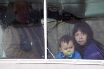 Doug Chilton, head of the One People Canoe Society, and Magnus and Alexa Jackson watch boats gather on Wednesday, June 8, 2016, near Juneau, Alaska. The One People Canoe Society began a canoe trip to Juneau from Angoon on June 2. Their landing on Douglas Island is the unofficial beginning of Celebration. (Photo by Rashah McChesney/KTOO)