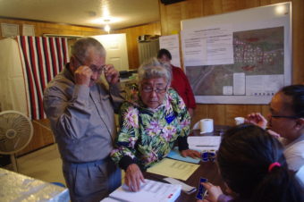 Anecia Toyukak helps her husband, Mike, look at the ballots in Manokotak on Aug. 16, 2016. (Photo by Molly Dischner/KDLG)