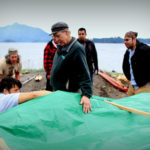 Master carver Steve Brown oversaw the steaming, while Jerrod Galanin takes a look under the tarp. (Photo by Emily Russell/KCAW)