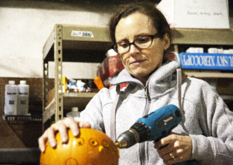 Amy Karpstein uses a drill to carve small holes into her pumpkin at Juneau Makerspace in Lemon Creek on Monday, October 24, 2016. Karpstein was one of seven people using the space Monday night during an open studio night. (Photo by Tripp J Crouse/KTOO)