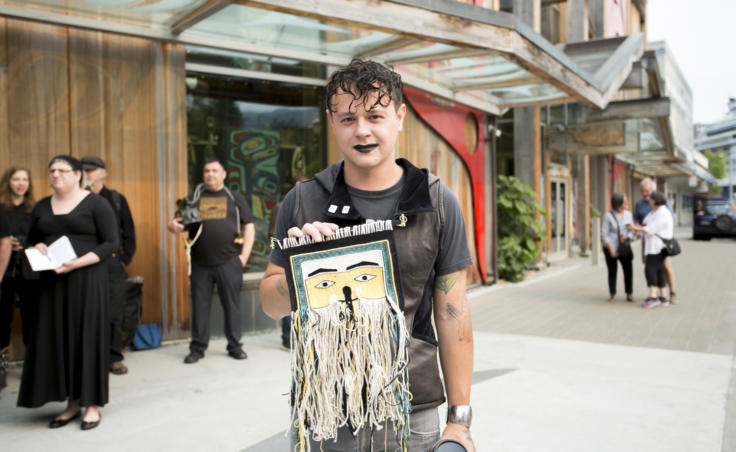 An artist holds a weaving outside the Sealaska Heritage Building