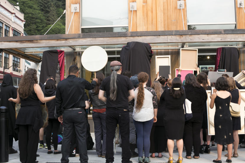 Artists dressed in black turn their back to the street