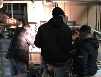 YKHC staff and RMWs working to fix Emmonak's damaged vacuum pump. (Photo by Adrian Wagner/KYUK)