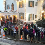Several people wait in line for the Alaska Governor Mansion annual holiday open house on Tuesdsay, Dec. 6, 2016 in Juneau. Musical entertainment and heaters were available for people under the tent, while some volunteers passed out hot apple cider and treats to those waiting in the open. (Photo by Tripp J Crouse/KTOO)