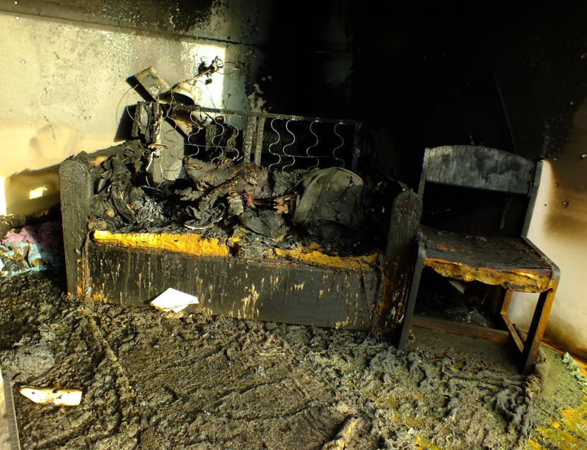 Aftermath of a fire in a staged room during a recent fire investigator training exercise at Juneau’s Hagevig Regional Fire Training Center. While the dead pig, dressed in clothes to mimic a human fatality, is burned on the upper exterior, the underside of the animal later showed little or no effects from the fire. (Photo by Matt Miller/KTOO)