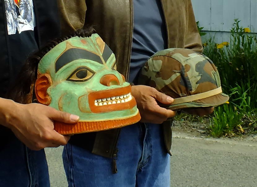 A Tlingit warrior helmet and a modern helmet are presented during a 2017 Memorial Day observance at Southeast Alaska Native Veterans Memorial Park. (Photo by Matt Miller/KTOO)