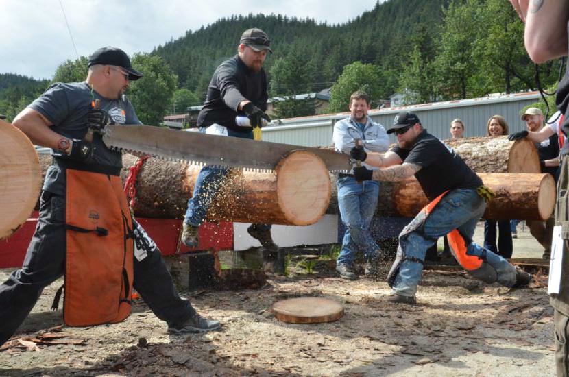 Two men compete in the team log bucking competition.