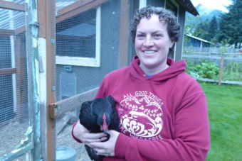 Sarah Dolan stands in front of her run and chicken coop holding a chicken on Saturday.