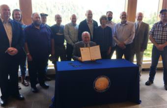Gov. Bill Walker hold up a signed Senate Bill 88, the Alaska Mental Health Trust land exchange. (Photo by Leila Kheiry/KRBD)