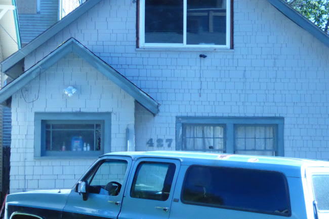 A white house with the number 427. A blue SUV sits in front of it.