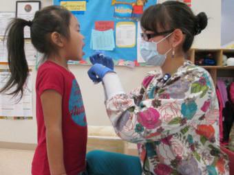 Dental health aide therapist Bonnie Johnson examining a child's teeth in the Emmonak YKHC Sub-Regional Clinic. (Photo courtesy Yukon-Kuskokwim Health Corporation)