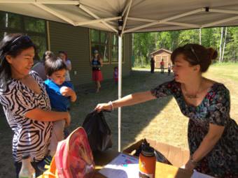 A volunteer distributes bags of food during the summer backpack meals program at the Talkeetna Public Library. (Photo by Anne Hillman/Alaska Public Media)