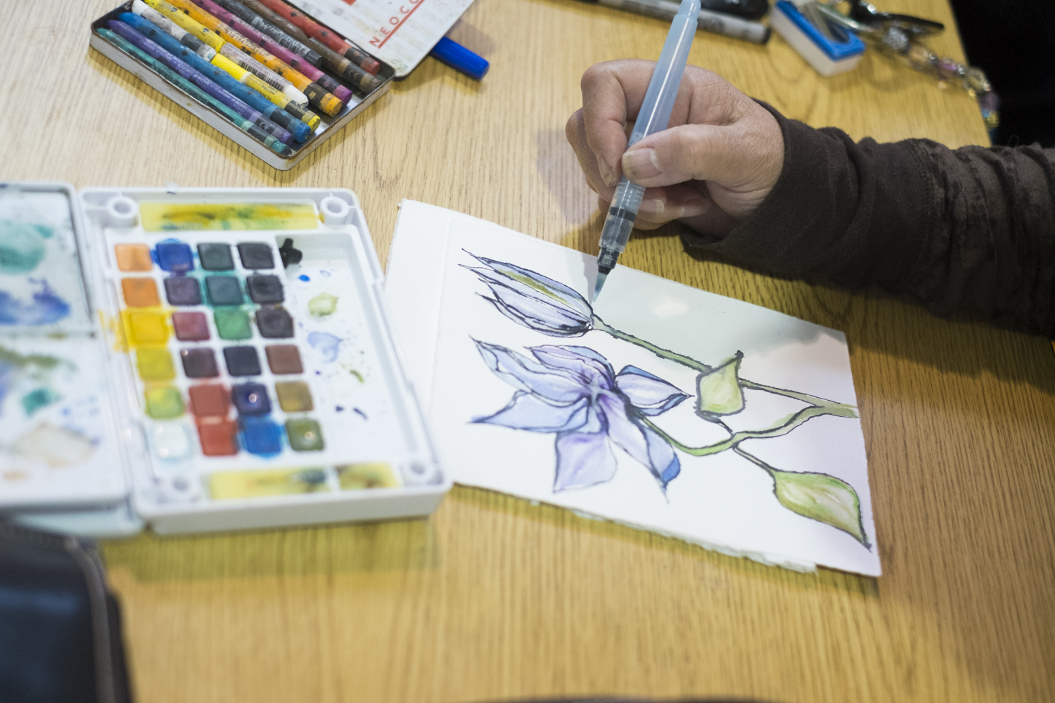 Pua Maunu uses watercolors and pen and ink to paint at Artists of All Nations, a communal art space at the JACC on Sunday, Sep. 24, 2017. (Photo by Annie Bartholomew/KTOO)