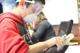 Tyler Croom polishes the caribou antler he is turning into a cribbage board. (Photo by Avery Lill/KDLG)