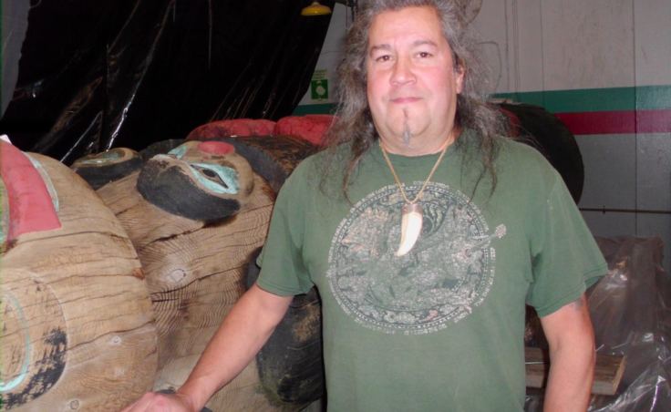 Tommy Joseph with the Chief Johnson totem pole. (Photo by Maria Dudzak/KRBD)