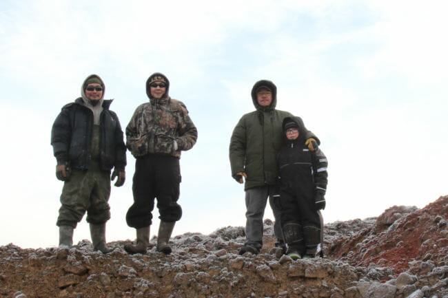 Of the rock quarry, Andrew John, Newtok's tribal administrator says, "This time last year, all this was just a dream!" Pictured with his son, Jason, at right, and Dalen Ayuluk, center. (Photo by Rachel Waldholz/Alaska's Energy Desk)
