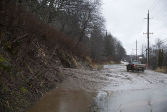 A truck drives through an open lane after a mudslide on Monday, Dec. 11, 2017, in Juneau. The slide happened near the intersection of Mill Street and Thane Road south of downtown Juneau. (Photo by Rashah McChesney/Alaska’s Energy Desk)