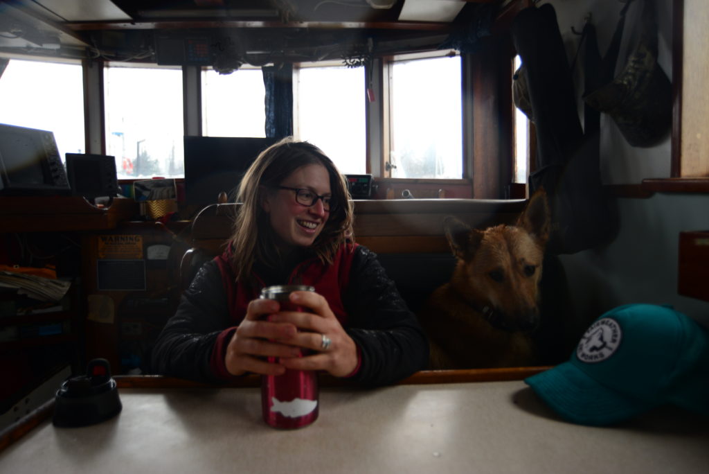 Capt. Lindsay Johnson on the F/V Sika, along with boat dog Tsirku, whose name is Tlingit for “big salmon.” (Photo by Berett Wilber/KHNS)