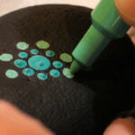 Heather Stemmerman uses a paint pen to create a design on a rock in Juneau. (Photo by David Purdy/KTOO)