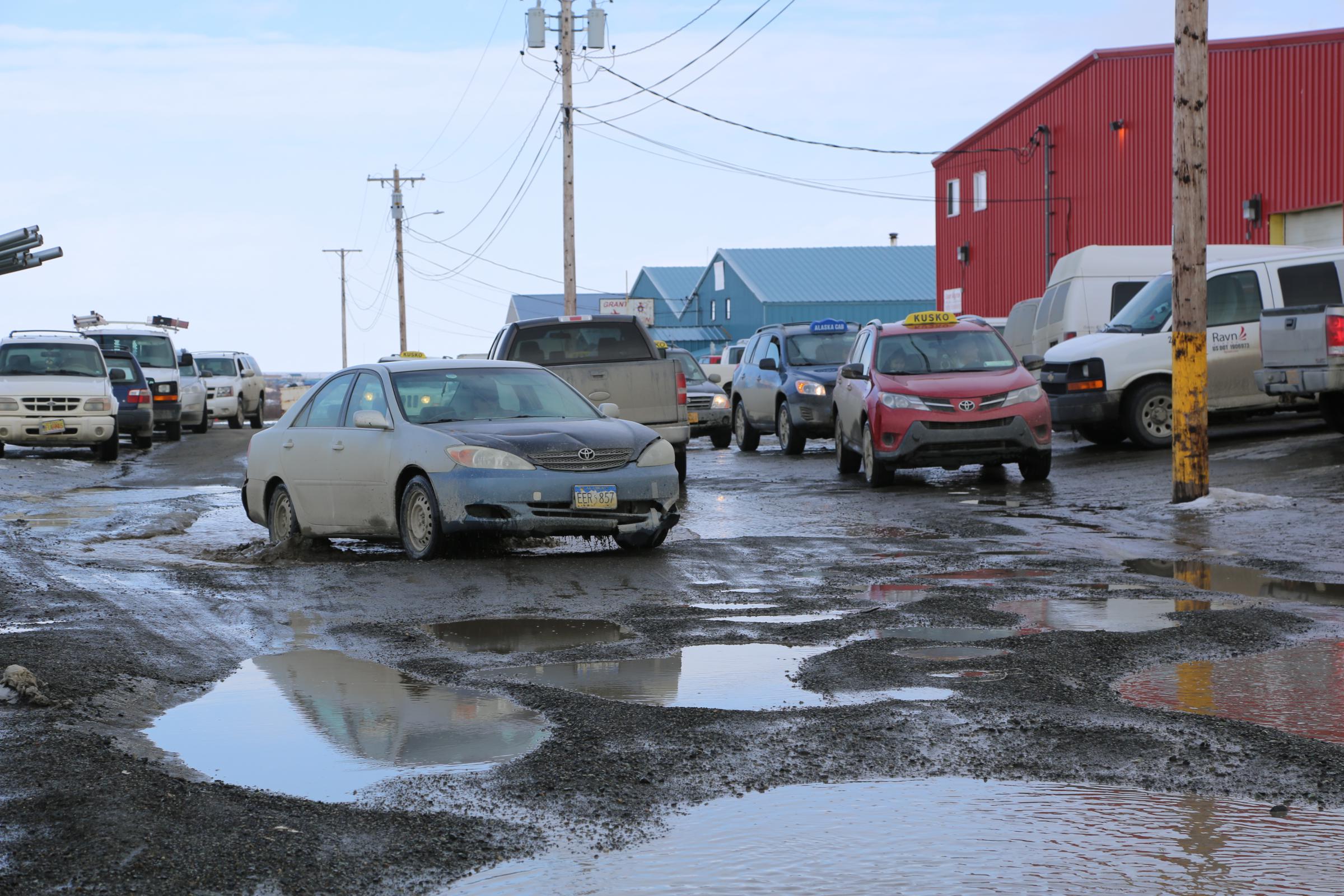 Drivers navigate the potholed road March 28, 2018, in front of the Ravn Air terminal, Bethel. (Photo by Amara Freeman/KYUK)