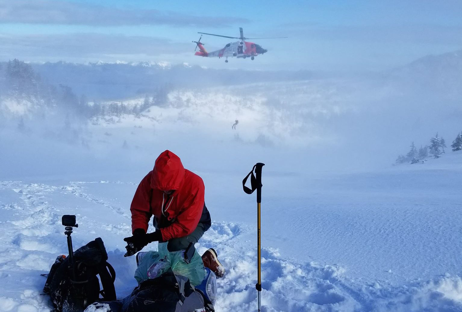 Roman Sorokin waits as USCG rescue swimmer Keith Williams descends from a Jayhawk helicopter in the distance (Photo courtesy Josh Joseph)