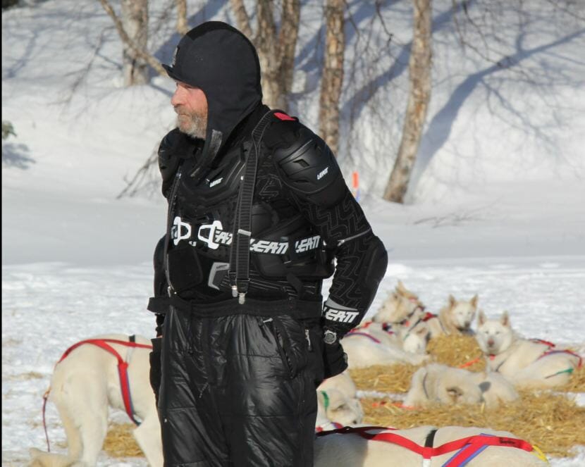 Jim Lanier handling his dogs at the Finger Lake checkpoint in his protective mountain biking gear. (Photo by Zachariah Hughes/Alaska Public Media)
