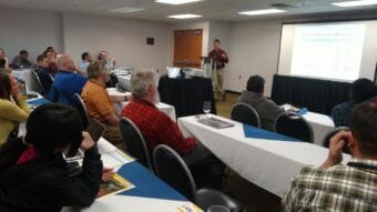 Fairbanks North Star Borough Energy Management Engineer Ben Loeffler talks with conferees about a biomass-gasification combined heat and power plant project at the Big Dipper Ice Arena during Tuesday’s Rural Energy Conference (Photo by Tim Ellis/KUAC)