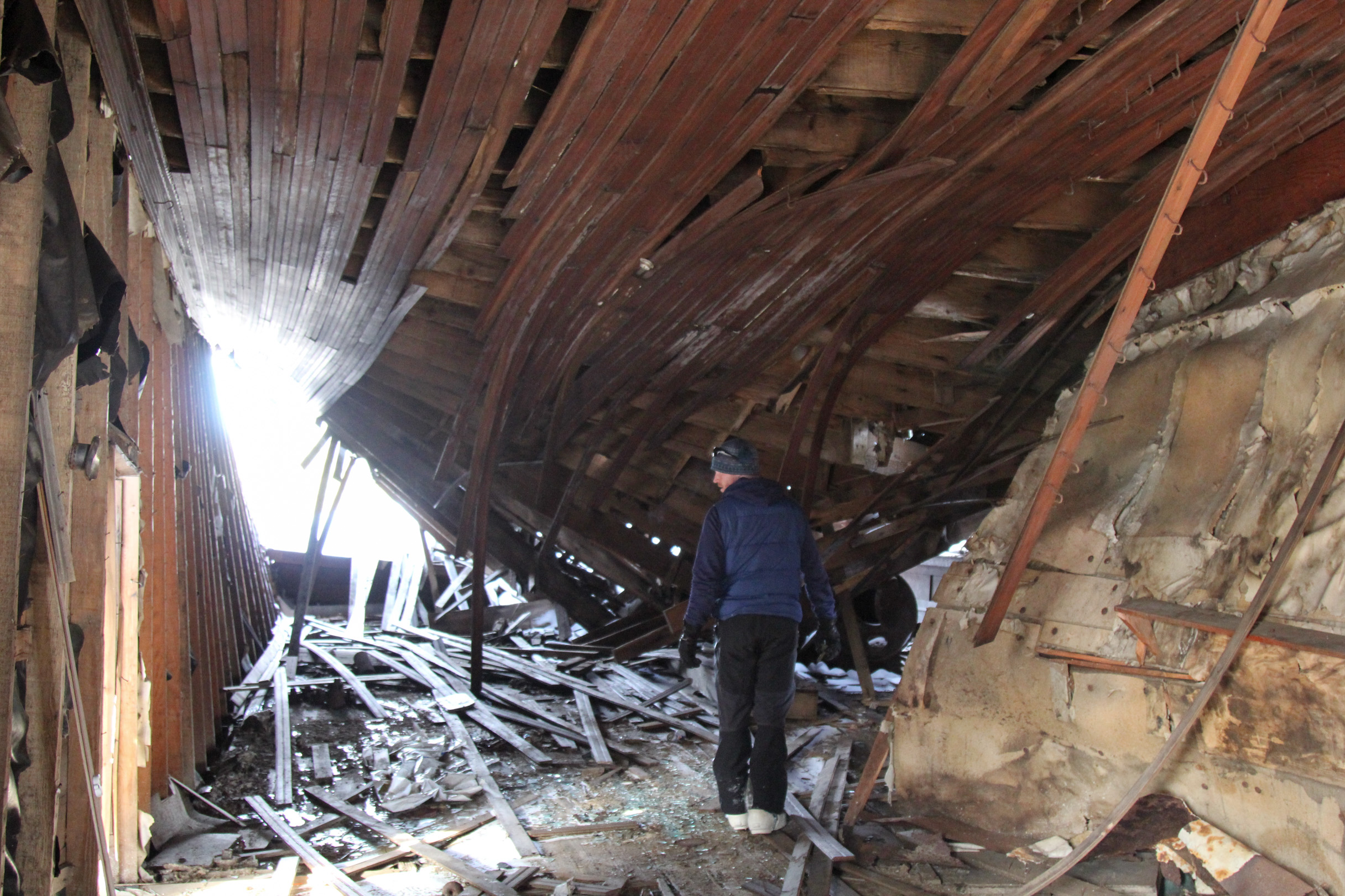 Woodsen Saunders explores a collapsed building at the Iditarod checkpoint from the historic site. (Photo by Zachariah Hughes/Alaska Public Media)