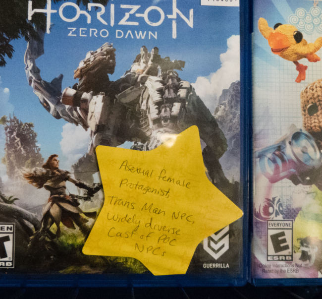 A video game box with a large yellow star stuck on the front. The star is labeled "Asexual female protagonist, trans man NPC, widely diverse cast of POC NPCs"