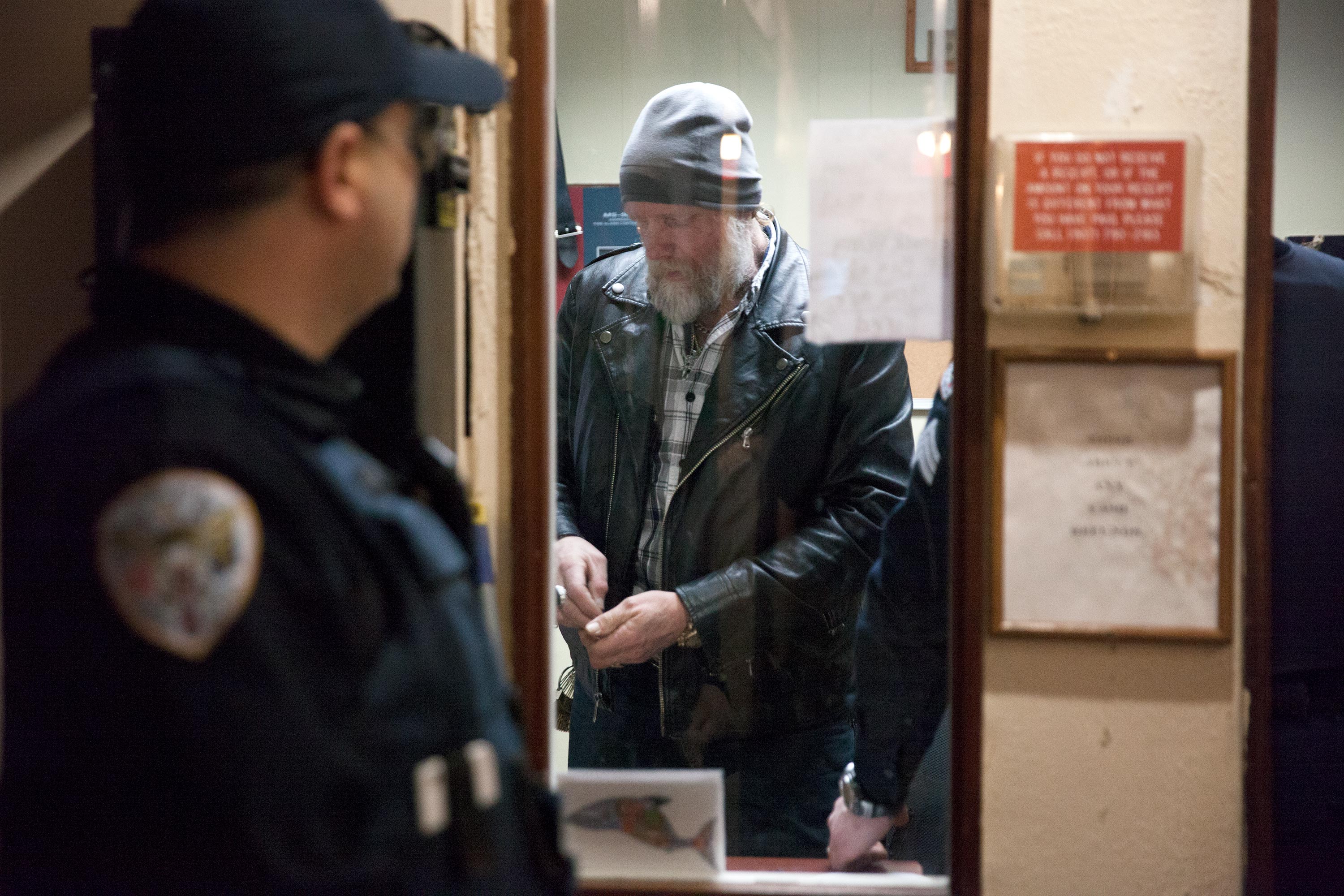 Juneau police officers confer as they arrest Chuck Cotten, property manager at the Bergmann Hotel. Cotten was responsible for removing residents from their rooms before Friday March 10, 2017 in Juneau, Alaska. The building has been condemned. (Photo by Rashah McChesney/Alaska's Energy Desk)