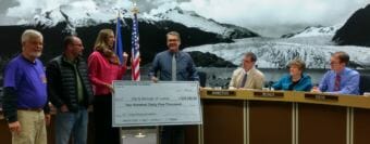Juneau Community Foundation Executive Director Amy Skilbred presents Juneau City Manager Rorie Watt a novelty check for $235,000 in donations for Project Playground on April 2, 2018.