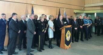 Alaska Gov. Bill Walker, flanked by more than 30 law enforcement officials, holds a press conference on Friday, May 18, 2018, at the state crime lab in Anchorage.