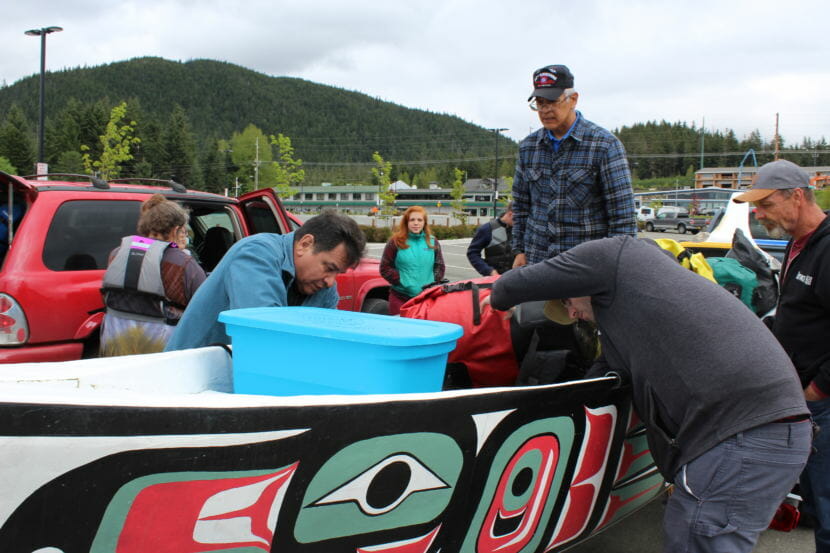Dennis Jack, center, looks on as Doug Chilton, right, and other paddlers pack supplies into the Eagle canoe that veterans will paddle. May 29, 2018.