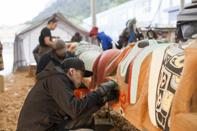 Traditional Arts Apprentice & Youth Mentor Shane Brown works on the Yanyeidí totem pole at Harborview Elementary School on May 29, 2018. (Photo by Annie Bartholomew/KTOO)
