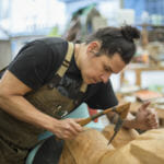 A carver uses an adze on a totem pole