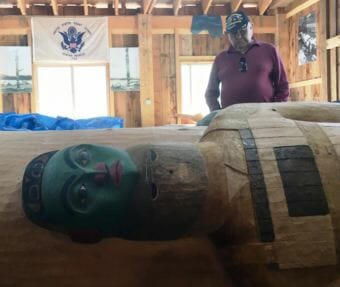Veteran and Klawock elder Aaron Isaacs looks at the veterans pole at the Klawock carving shed in early July. The pole will be raised Aug. 18. (Photo by Leila Kheiry/KRBD)