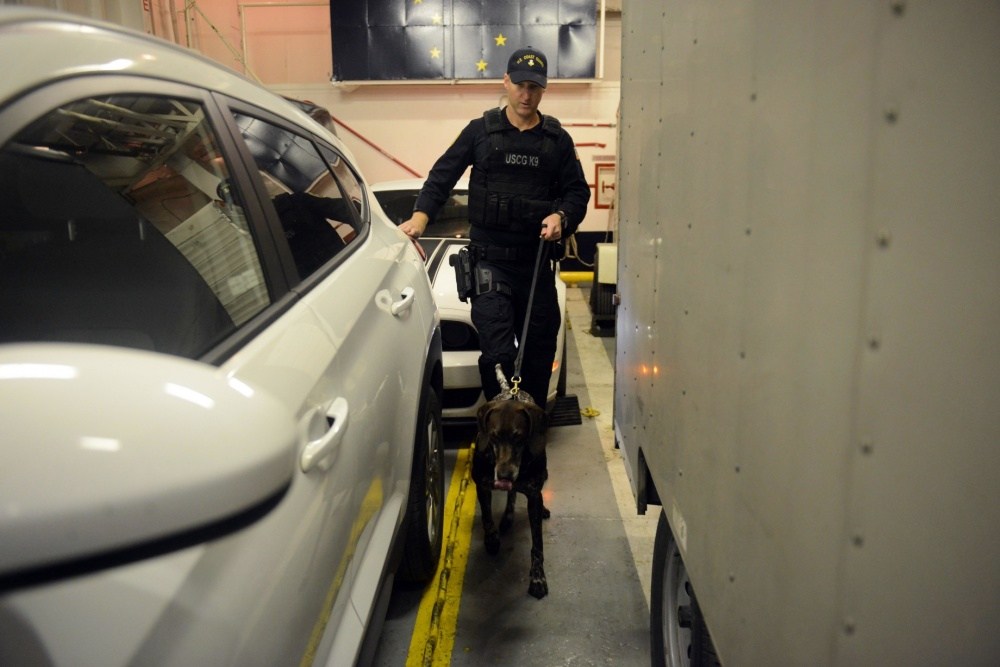Petty Officer 1st Class Devon Waite and K9 Bingo conduct a vehicle sweep aboard the ferry vessel Tustumena in Kodiak. (Photo by Lauren Dean/U.S. Coast Guard)
